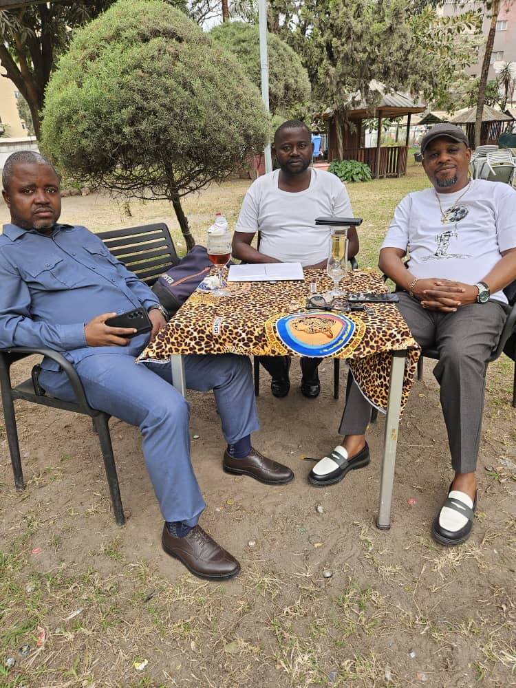 Trois cadres d’ARCHE DU CONGO réunis autour d’une table en extérieur